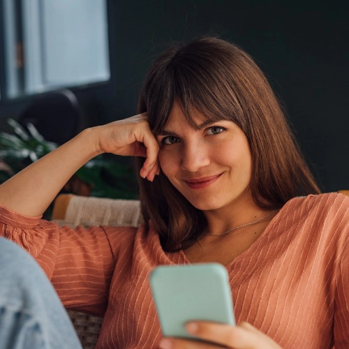 young woman on her couch with her phone